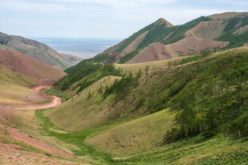 panoramic view of road between of green hills
