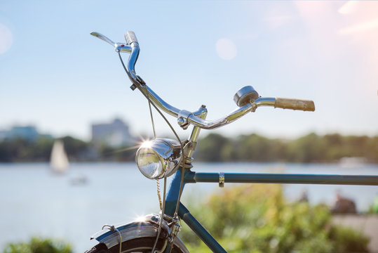 partial view of vintage blue bicycle with handlebar and light under blue summer sky