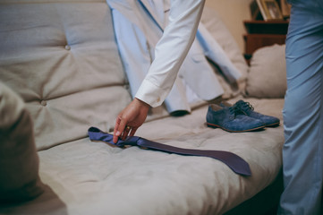 The groom in a suit corrects a tie. Groom's accessories
