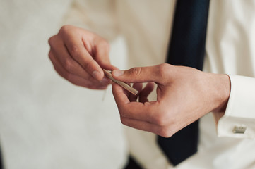 The groom in a suit corrects a tie. Groom's accessories