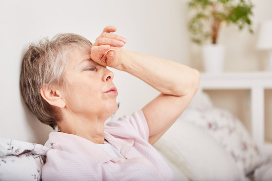 Seniorin mit Kopfschmerzen liegt im Bett