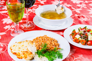 Three plates with lunch dishes on table. Vegetable salad, fish soup and chicken schnitzel with spelt garnish. Armenian food