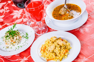 Three plates with lunch dishes on table. Salad, soup with meatballs and pilaf. Armenian food