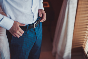 Groom holding hands on the belt, wedding suit