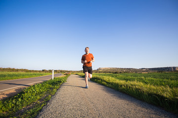 Fototapeta premium Man running outdoor sprinting for success. Male fitness runner sport athlete in sprint at great speed in beautiful landscape
