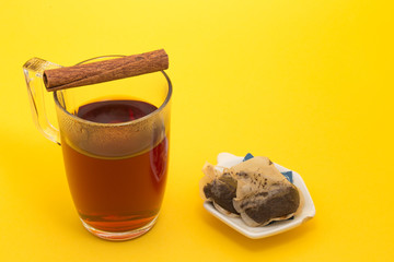 A glass mug with black tea and a cinnamon stick on top of it