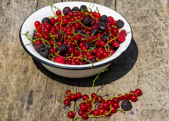 Fresh colorful berries in bowl on rustic wooden table