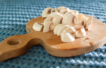 The process of cutting champignon mushrooms on a wooden cutting board