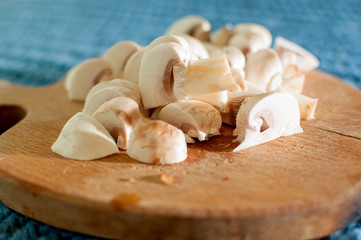 The process of cutting champignon mushrooms on a wooden cutting board