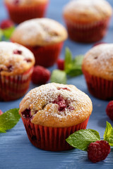 Sweet homemade raspberry muffins on wooden table.
