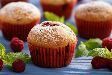 Sweet homemade raspberry muffins on wooden table.