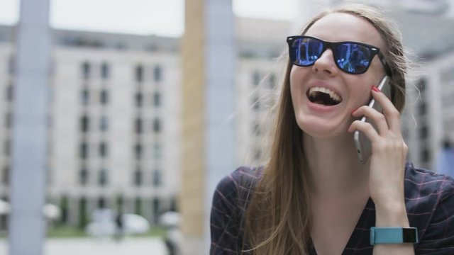 Woman With Dark Glasses Laughing During a Phone Call