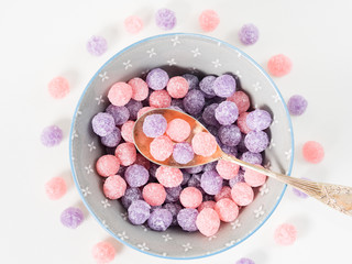Obraz na płótnie Canvas Round purple and pink bonbon candies sweets in gray bowl on white canvas background. Minimal still life
