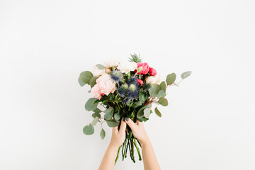 Girl's hands holding beautiful flowers bouquet: bombastic roses, blue eringium, eucalyptus, isolated on white background. Flat lay, top view. Floral composition