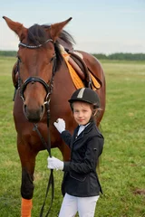 Foto op Canvas Pretty little girl jockey lead horse by its reins across country in professional outfit © Alex Shadrin