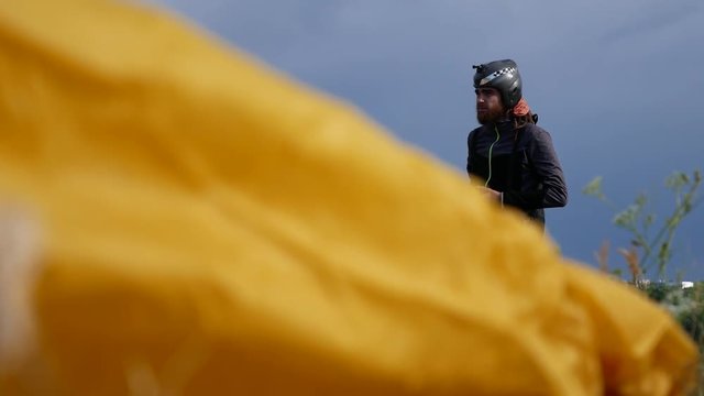 Man Is Preparing To Fly On A Paraglider. Person Before Flying On Paraglider On Sunny Day. Before Man Paragliding An Extreme Sports Event On A Paraglider