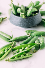 Fresh green peas in beautiful dark often in rustic style on a marble table. Summer vegan concept