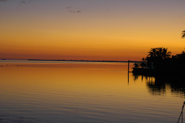 Fototapeta na wymiar twilight over ocean by dock orange and yellow skies