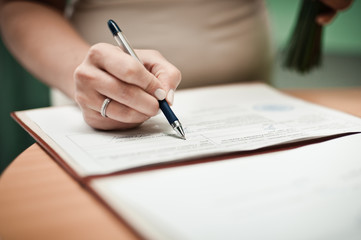 Fototapeta premium Signature Ceremony. The bride and groom sign the documents about the marriage