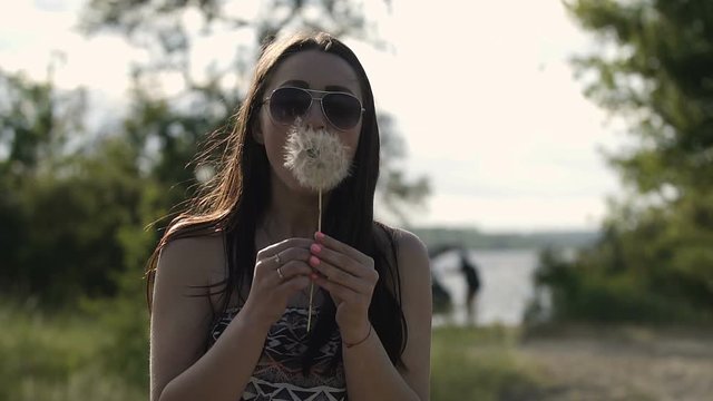The girl blows away the dandelion