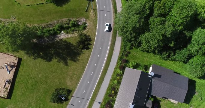 Car driving in a countryside town, Cinema 4k aerial view following a white car driving on a road through Korpo town, on a sunny summer day, on a island in the finnish archipelago
