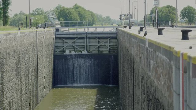 Huge door at overflow cargo lock chambers. Water dam on river with pass. Transport building for waterway navigation on river. Dripping water over surface.