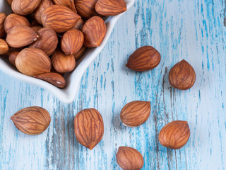 Heap of brown apricot kernels on wooden background close up