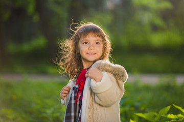 Beautiful girl with long hair in motion whirls and smiles, during sunset in the park. The concept of childhood and freedom.