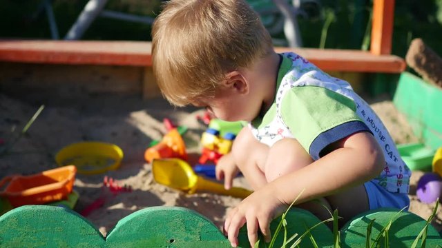 the child plays with the toys in the sandbox.Summer Sunny day. Fun and games outdoors