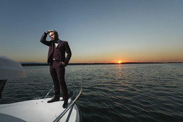 Fototapeta premium Handsome man on sailing boat in sunset.