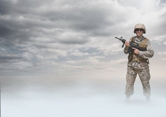Soldier man holding a weapon against desert background