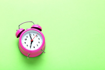 Pink alarm clock on the green background