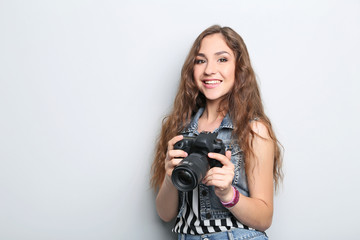 Portrait of young woman with camera on grey background