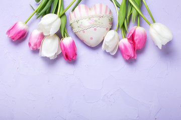 Obraz na płótnie Canvas Border from tulips flowers and decorative heart on violet textured background.