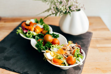 Delicious fresh vegan raw paleo vegetarian salad with cherry tomatoes, shredded cabbage and carrot served on chalk board