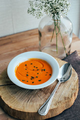 Deep plate or bowl of spanish tomato soup gazpacho or salmorejo seasoned with herbs and olive oil, served on wooden board