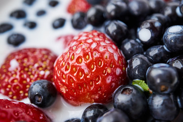 Strawberries, blueberries and milk in a white bowl