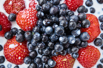Strawberries, blueberries and milk in a white bowl