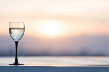 A glass with a white wine in the light of the setting sun. Vibrant alcohol background.