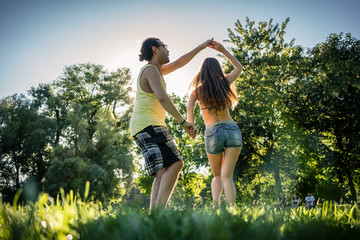 Mann turning woman dancing in the grass in summer park