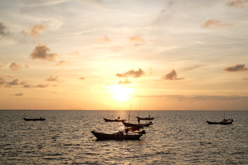Beautiful sunset and silhouette fisherman boat in the ocean