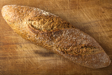 Brown baguette with seeds on wooden background