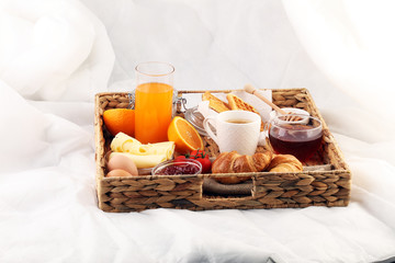 breakfast in bed with fruits and pastries on a tray -waffles, croissants, coffe and juice