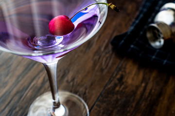 Blue Moon Cocktail with cherry on wooden surface.