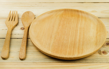 Wooden plate, wooden fork and wooden spoon on wooden talbe