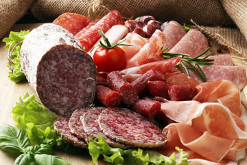 Food tray with delicious salami, pieces of sliced ham, sausage, tomatoes, salad and vegetable - Meat platter with selection