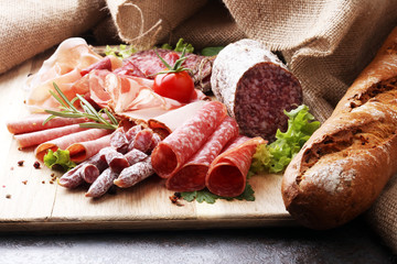 Food tray with delicious salami, pieces of sliced ham, sausage, tomatoes, salad and vegetable - Meat platter with selection