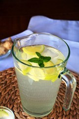 Fresh cold lemonade with a piece of lemon, ice and ginger on a glass.