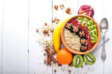 Healthy food: porridge with fruit kiwi, banana and nuts. On Wooden background. Top view.