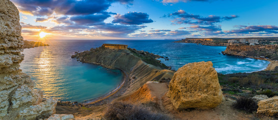 Mgarr, Malta - Panorama of Gnejna bay and Golden Bay, the two most beautiful beaches in Malta at sunset with beautiful colorful sky and golden rocks taken from Ta Lippija - obrazy, fototapety, plakaty